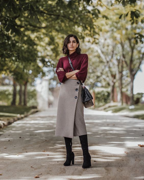 a purple oversized sweater, a plaid midi wrap skirt on buttons, black tall boots and a black bag