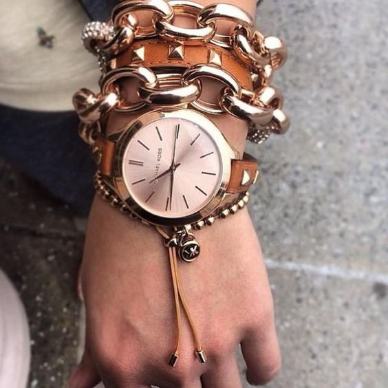 a stack fo rose gold bracelets - heavy chains and a leather studded one plus a watch on a studded leather strap
