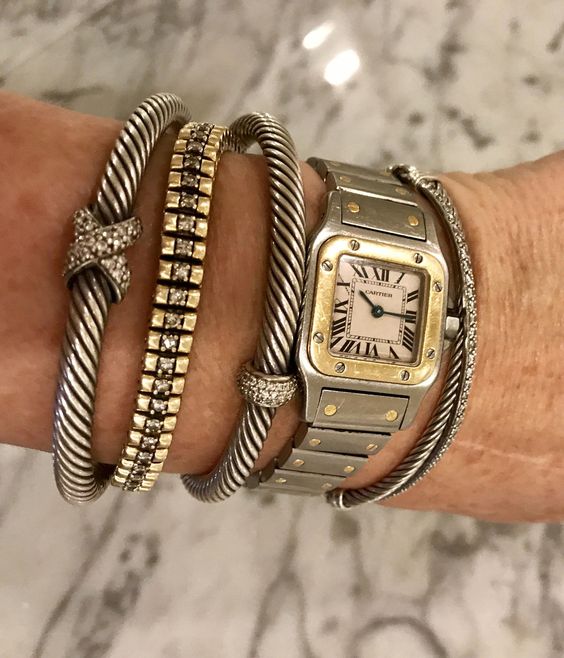 a stack of bold metallic bracelets with pretty embellished charms and a watch - all the pieces are statement ones