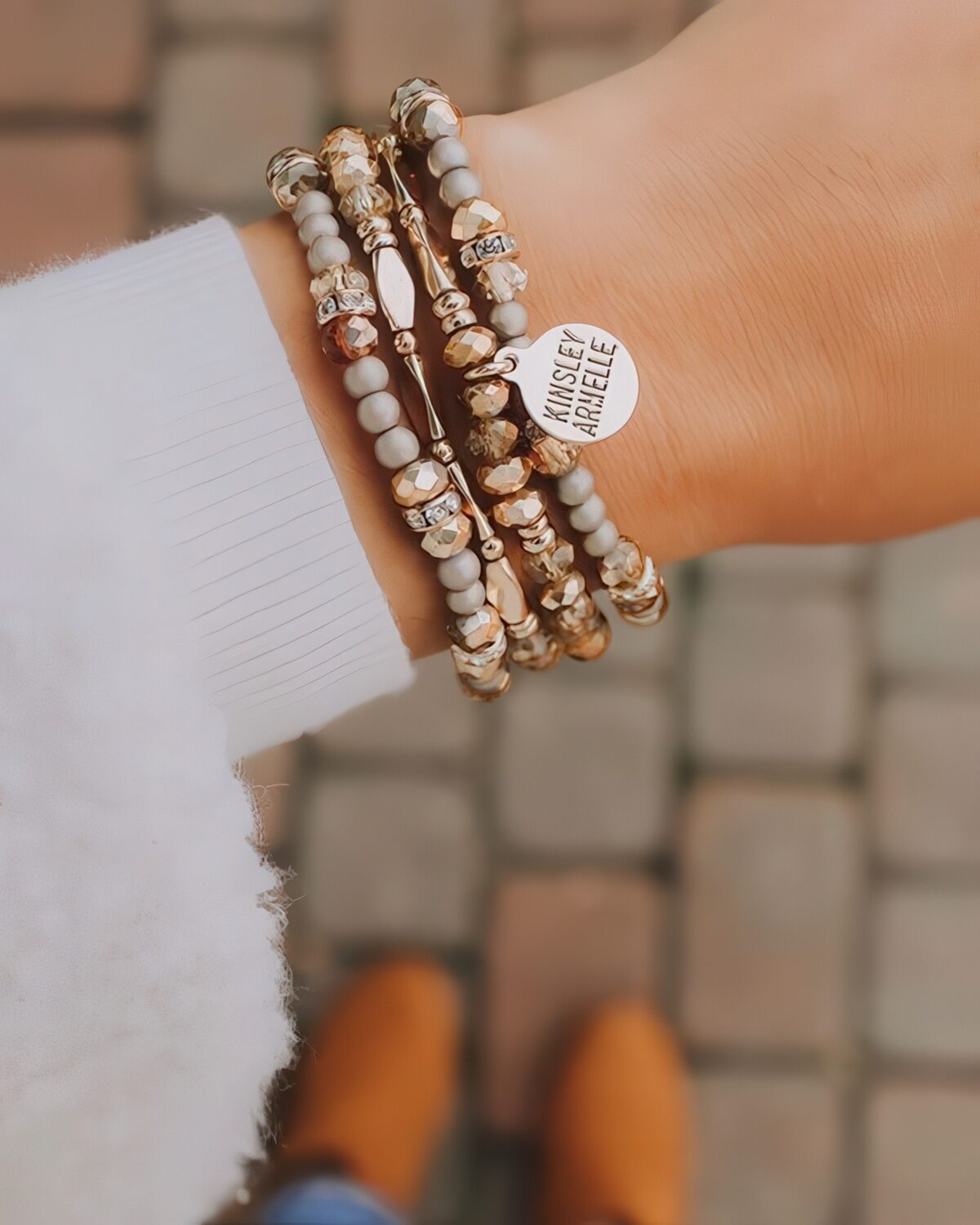 a stack of chic and elegant bracelets with gold and stone beads plus a personalized metal tag for an ultimate look