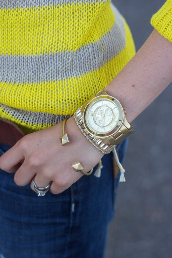 a stack of gold and silver bracelets -cuffs, embellishments and a matching watch as the main piece