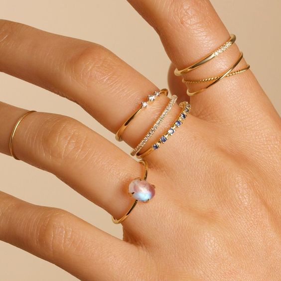 thin stacked gold rings with diamonds and a moonstone are different in textures and shapes and create a catchy look