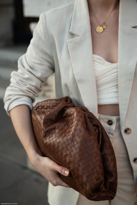 a woven brown leather soft clutch is a fashion statement - inspite of its classic color, it features a woven structure