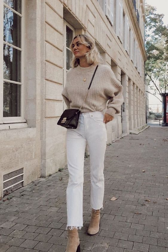an oversized sweater, white jeans with a raw hem, neutral booties and a black bag