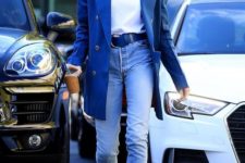 a Hailey Baldwin rocking a bold look with a white tee, blue jeans, blue lace up booties and an oversized jacket