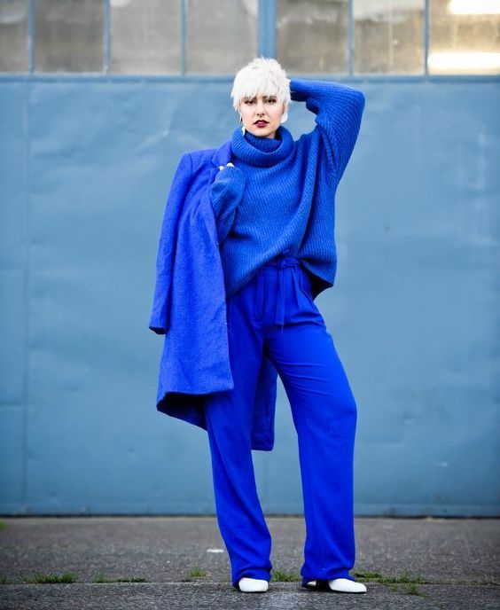 a bold classic blue monochrome outfit with an oversized sweater, pants, a coat and white boots