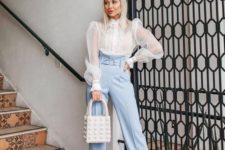 a chic work outfit with light blue high waisted pants and a white sheer puffy sleeve blouse, nude shoes and an embellished bag