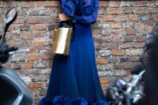 a classic blue midi A-line dress with ruffled sleeves and a feather skirt, silver shoes and a gold clutch
