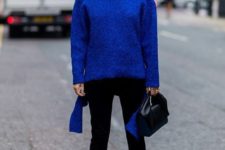 a classic blue oversized sweater, black jeans, white shoes, a black bag and statement earrings