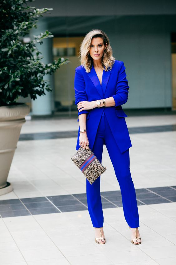 a classic blue pantsuit, silver shoes and a printed clutch for a bold work look is a chic idea