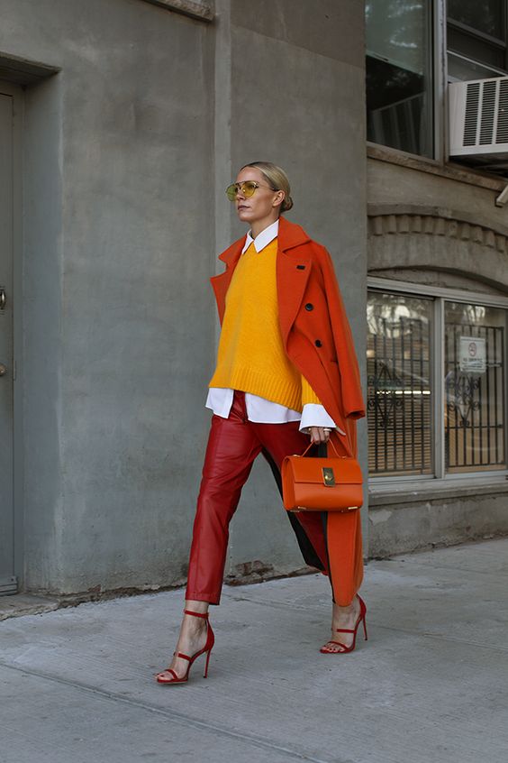a colorful look with red leather pants, a marigold sweater, a red coat and bag plus strappy heels