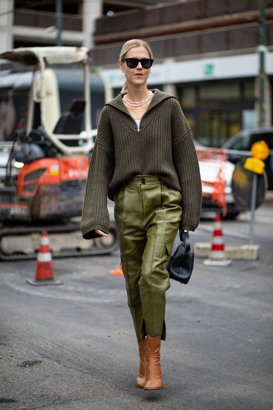 a dark green oversized sweater, light green leather pants, a navy bag and amber booties