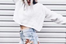 a white oversized chunky knit crop sweater paired with whitewashed embroidered jeans for a bold look
