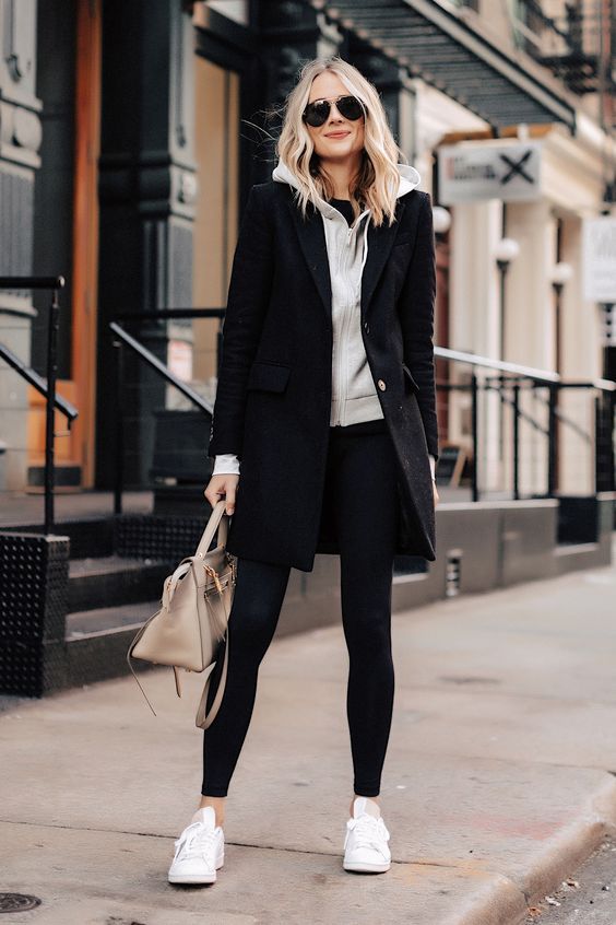 a sporty look with a grey hoodie, black leggings, a black coat, white sneakers and a neutral bag