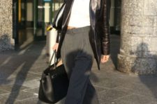 Bella Hadid wearing a white crop top, grey striped pants, black sneakers and a black leather blazer