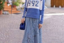 With blue and white labeled sweatshirt, blue bag and colorful sneakers