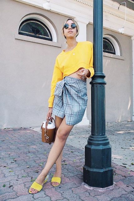 With yellow cropped shirt, brown mini bag and yellow mules
