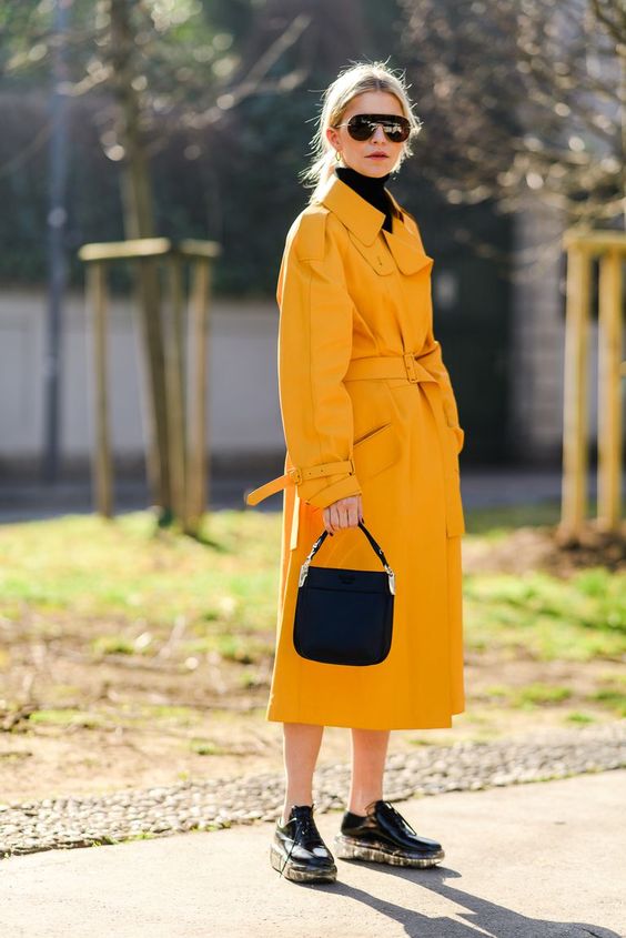 a bold spring look in black and sunny yellow, with a black turtleneck, a black bag, black platform shoes and a sunny yellow trench