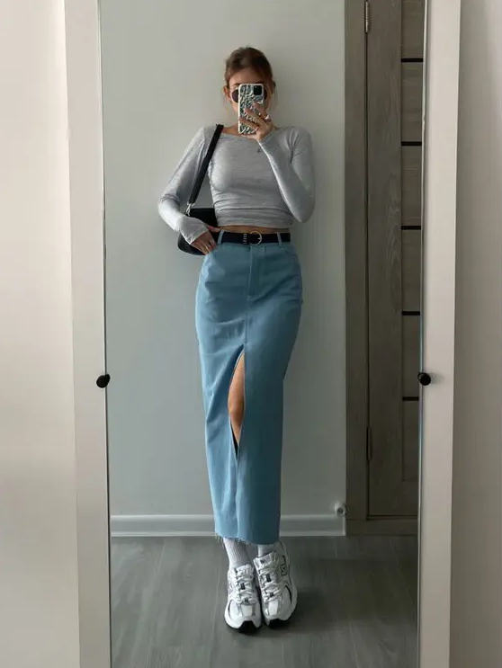 a grey crop top with long sleeves, a blue maxi skirt, white sneakers, a black belt and a black bag are a cool look for spring