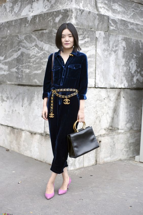 a navy velvet jumpsuit in 70s style, a chunky chain belt with logos, pink shoes and a black bag for a bold work look