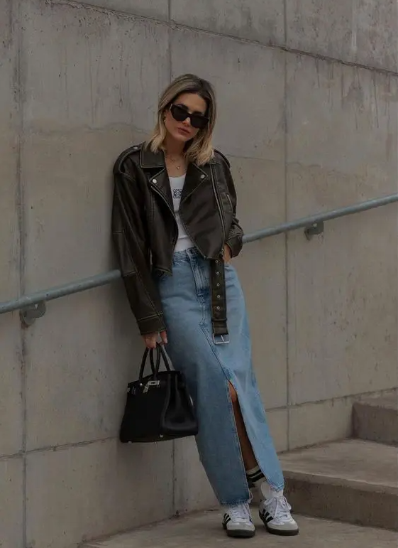 a pretty spring look with a tee, a blue denim maxi skirt, a black leather jacket, sneakers and a black bag
