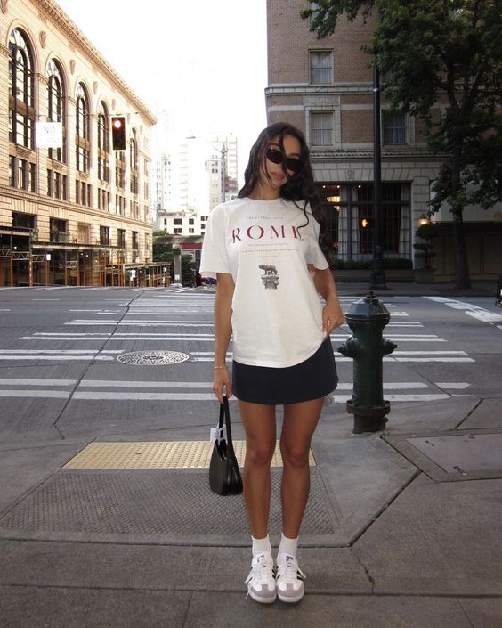 A summer look with an oversized white t shirt, a black mini, neutral sneakers and socks, a black bag is easy to repeat