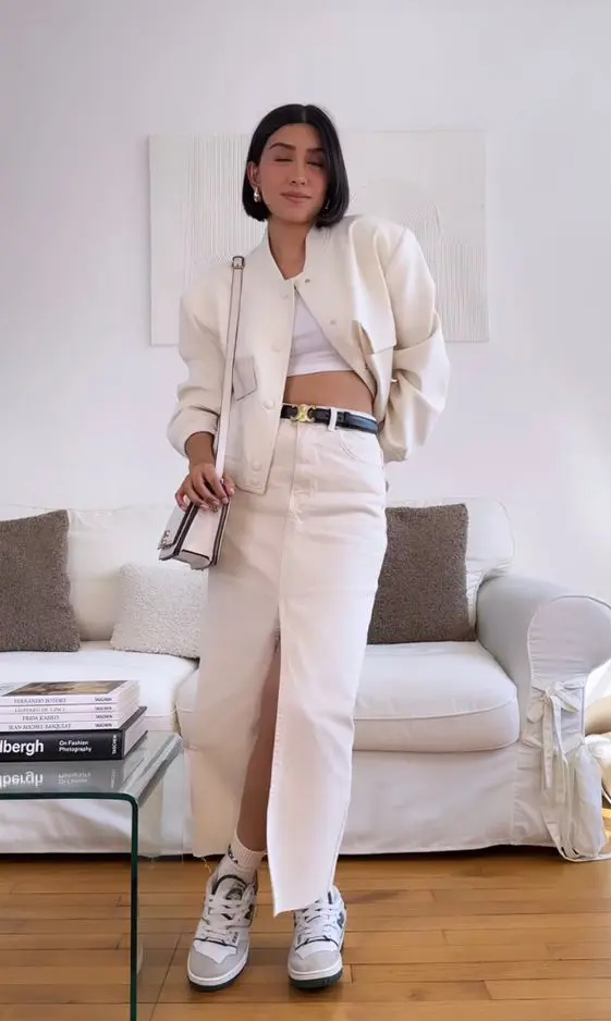 a white crop top, a white denim maxi skirt with a black belt, a white bomber, a bag and trainers