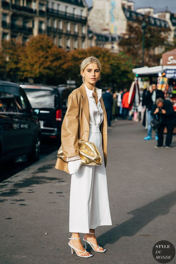 a white shirt, white culottes, white square toe shoes, a camel oversized leather jacket and a gold shiny clutch