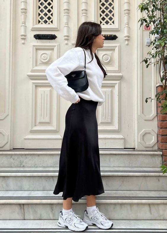 a white sweatshirt, a black satin midi, white trainers and socks, a cool black baguette bag for spring