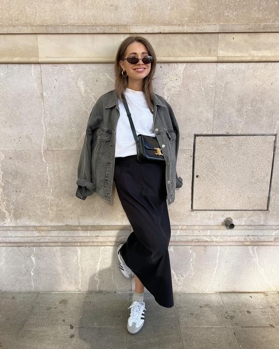A white t shirt, a black satin skirt, a grey denim jacket, white sneakers and a black baguette bag for spring