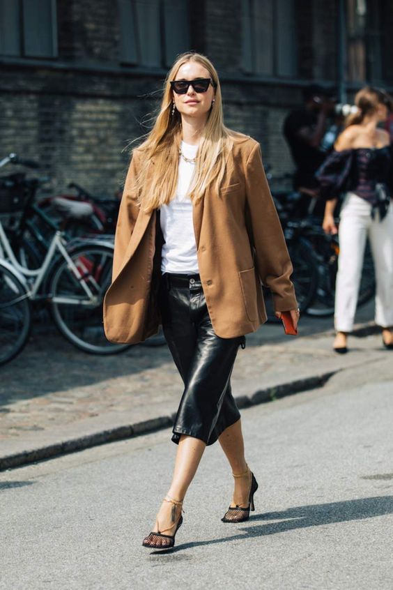 a white tee, a black midi leather skirt, an oversized camel blazer ad black wire square toe shoes