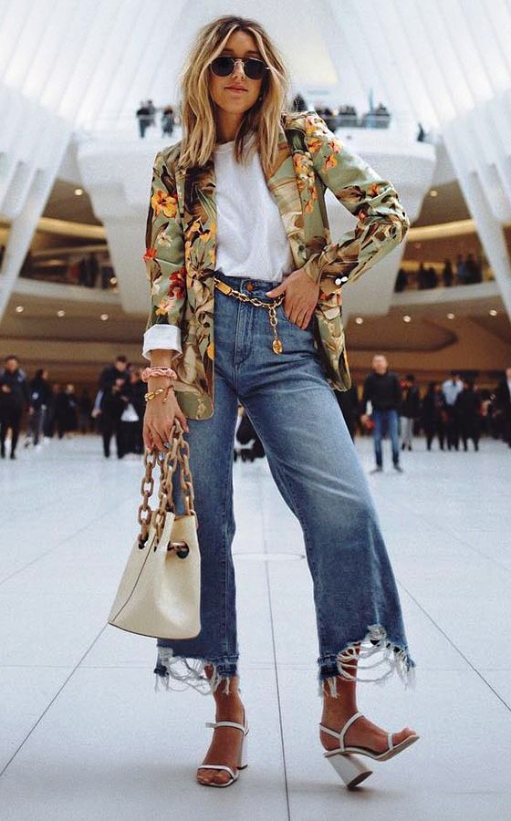 a white tee, blue jeans with ripped hems, a gold chain belt, a floral blazer, white shoes and a white bag on chains