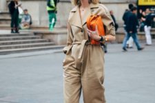 an oversized tan jumpsuit with a sash, leopard print shoes, an orange woven leather clutch for a bright touch