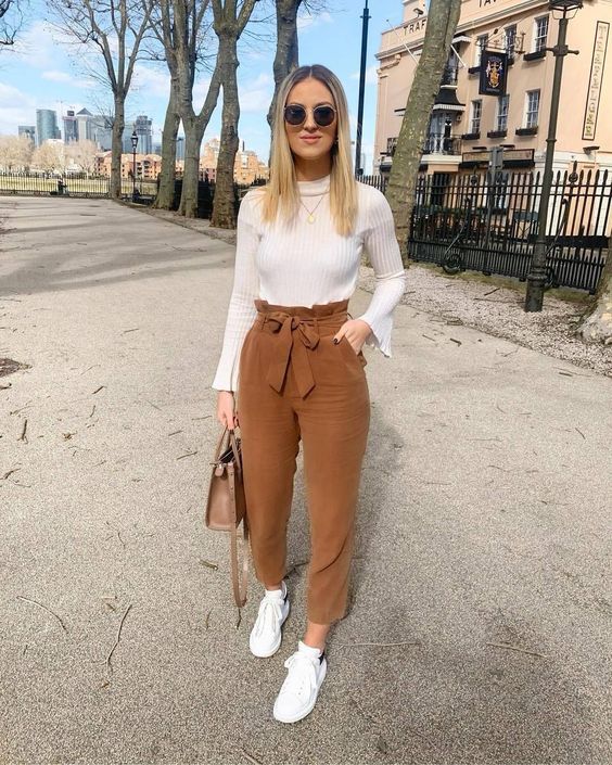 a casual fall outfit with a white top, brown velvet paper bag pants, white sneakers and a brown bag