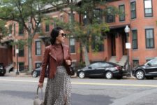 With brown turtleneck, brown leather jacket, ankle strap shoes and gray bag