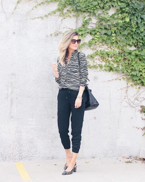 With navy blue jogger pants, black bag and zebra printed shoes