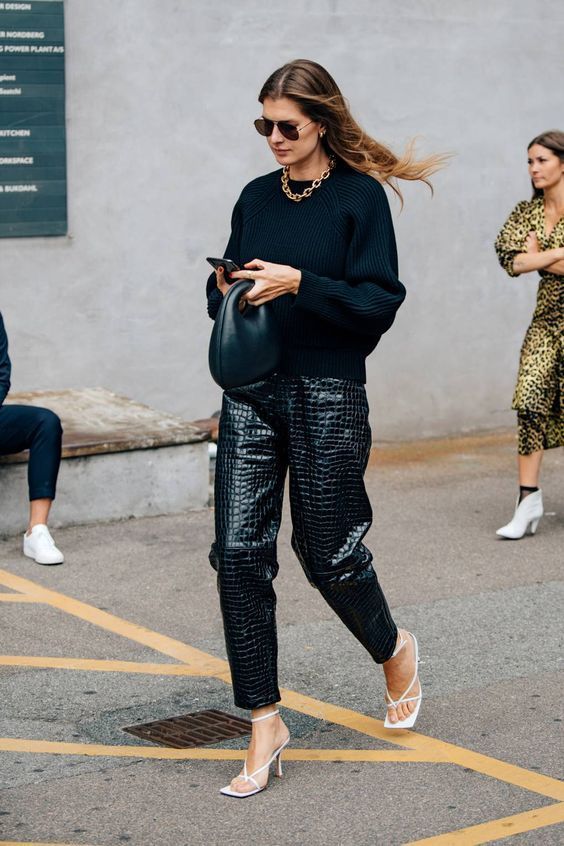 a black oversized sweater, black crocodile leather pants, white strappy shoes and a statement necklace