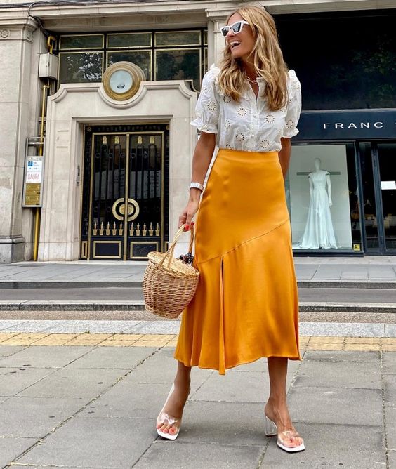 a boho blouse, a marigold satin midi skirt, white slipper mules, a basket instead of a bag are a cool outfit
