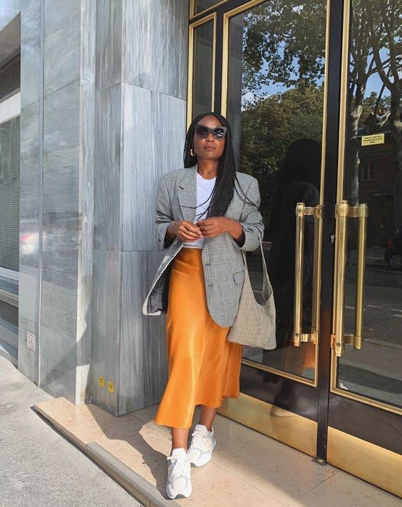 a catchy spring look with a white t-shirt, a marigold satin midi skirt, a grey oversized blazer, white trainers and a neutral tote