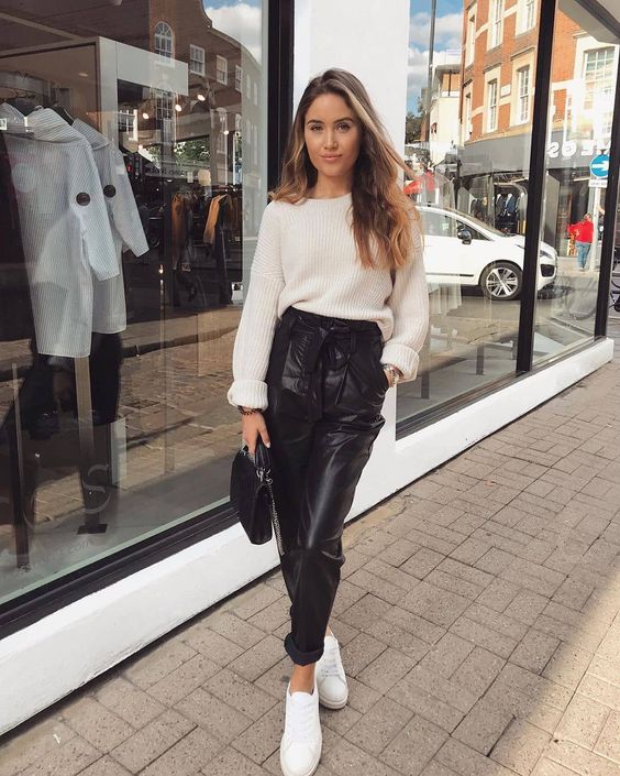 a chic and simple casual outfit with a white sweater, black leather high waisted pants, white sneakers and a black bag
