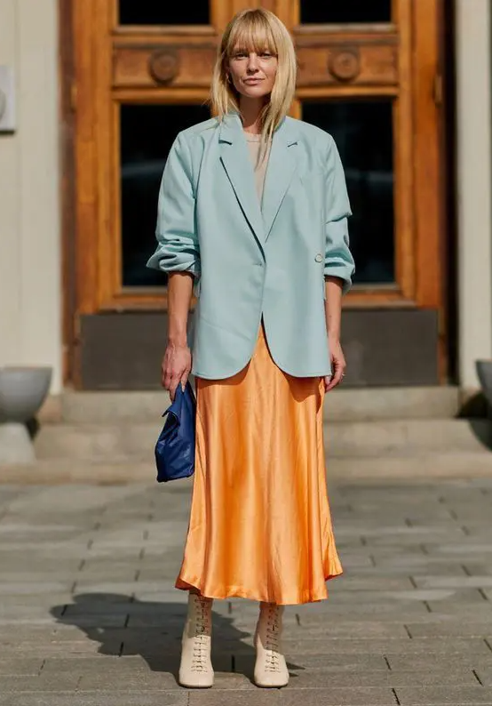 a colorful spring outfit with a neutral top, a bold yellow slip midi skirt, nude booties and a bold blue bag