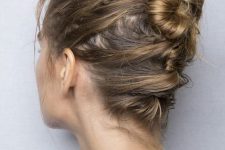 a messy ballerina bun made on top and with messy hair secured to keep it in place