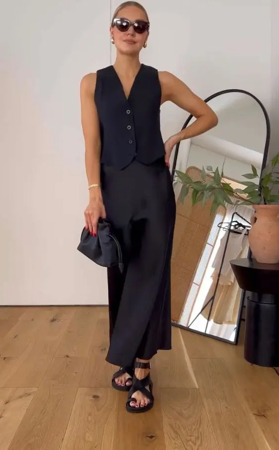 a refined black look with a waistcoat, a slip maxi skirt, lace up sandals, a small bag and chic jewelry