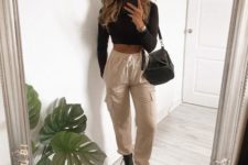 a sexy look with a black crop top with long sleeves, tan cargo pants, black army boots and a black bag
