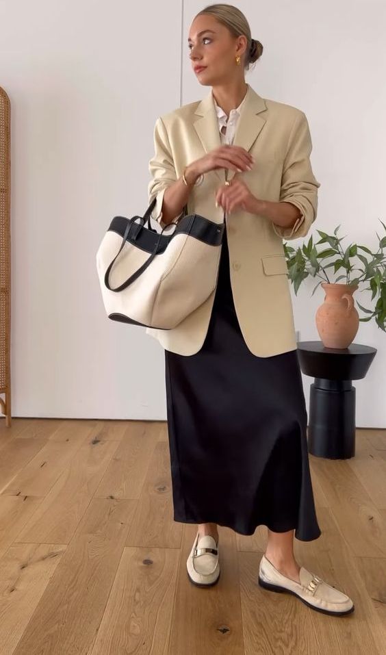 a spring office look with a white button down, a black satin maxi skirt, a neutral oversized blazer, white loafers and a large striped tote