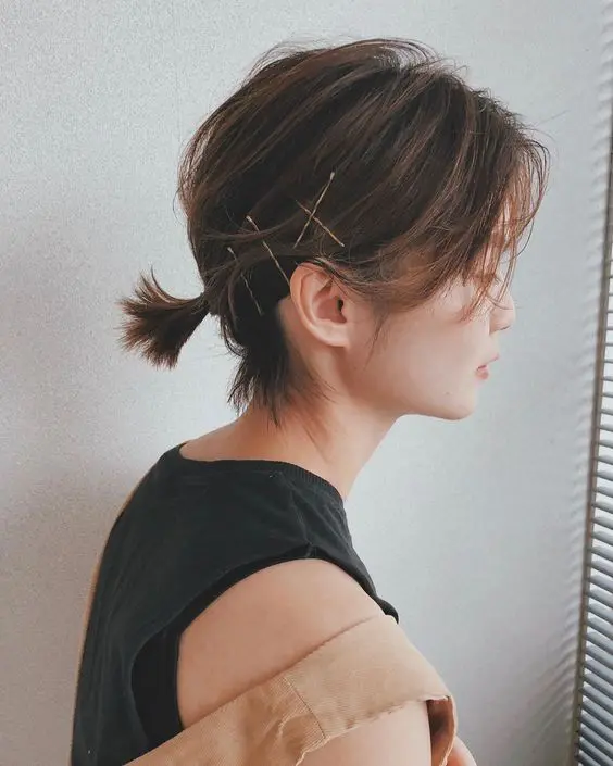 a super short low ponytail with side bangs and bobby pins for an accent is a cool and catchy idea