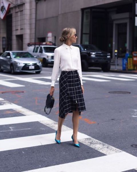 a white shirt, a windowpane print asymmetrical midi skirt, blue shoes and a black bag