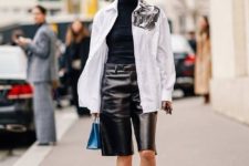an everyday look with a black turtleneck, a white oversized jacket, white trainers, black leather bermudas and a blue bag
