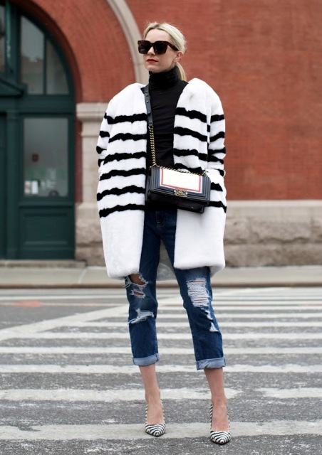 With black turtleneck, distressed jeans, white and black fur coat and chain strap bag