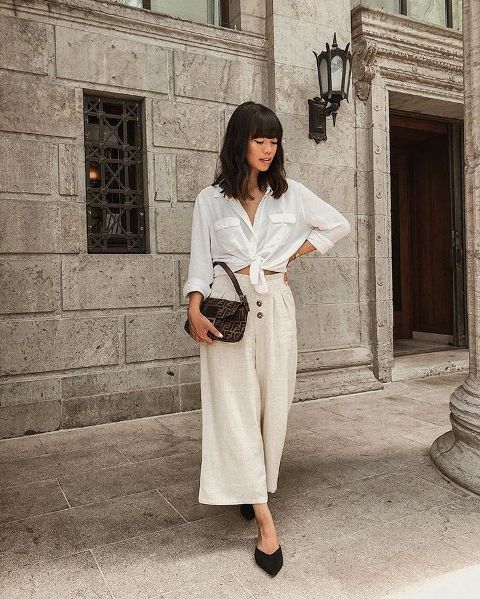 With white shirt, printed bag and black flat mules